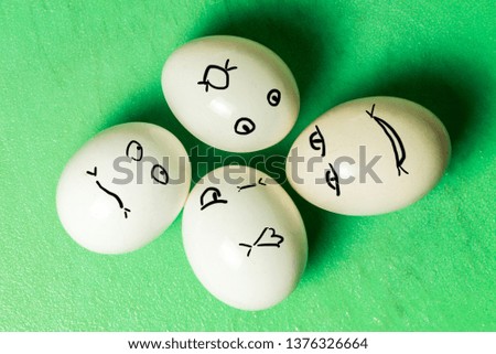 four white eggs with different face grimaces on green board. Horizontal frame