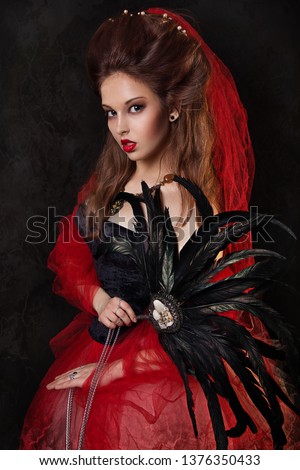 close up portrait of beautiful girl with red dress and feathers