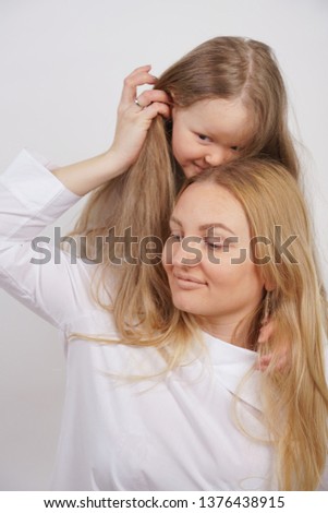 real family of caucasian mother and daughter in white shirts in the studio background