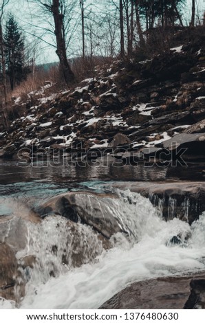 river in the mountains with swirling stream of water. Big boulders in mountain creek background. Little waterfall close up. Bukovel, Ukraine in winter season