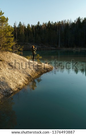 Young woman takes travel photos -Beautiful turquoise lake in Latvia - Meditirenian style colors in Baltic states - Lackroga ezers