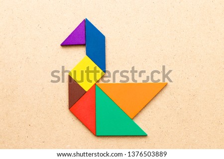 Color tangram puzzle in swan shape on wood background