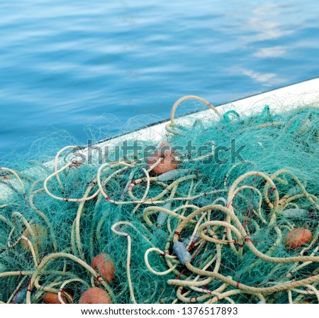 A fishing net with floats and sinkers, in a small fishing boat, light blue background, selective focus.