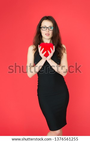 Fall in love. Woman elegant black dress hold heart soft toy. Love from first sight. Woman stylish dress and eyeglasses hold symbol love. Romantic concept. Girl in love dating. Happiness in her hands.