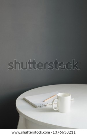coffee cup with sketchpad and pencil on white wooden table in scandi kitchen interior, vertical stock photo image with copy space for text
