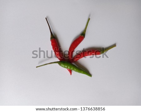 Picture of chilli used for cooking. There are 3 green chillies and 1 red pepper on a white background.