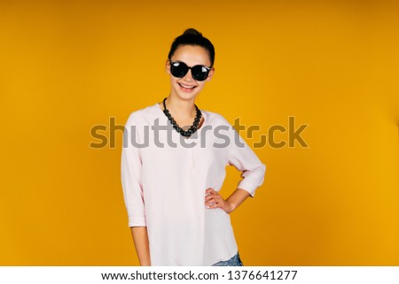 Cheerful woman in sunglasses on a yellow background