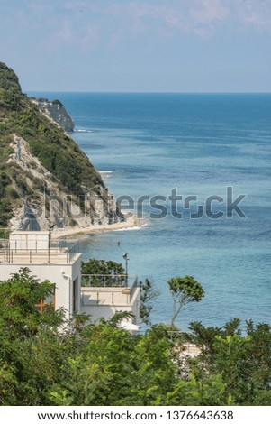 Beautiful seascape, aerial view of turquoise blue water surface, wild greenery and panoramic house terrace above sea coast, rocks and sandy sunny beach. Natural colorful summer widescreen background.
