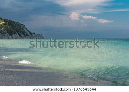 Beautiful seascape, green and turquoise tones and shades on flat sea water surface, blue sky grey pink clouds before storm at sunset evening time. Natural colorful pattern background, widescreen frame
