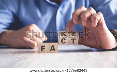 Man holding wooden cubes. Fact or fake. Business concept Royalty-Free Stock Photo #1376682443
