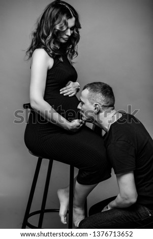 
Pregnant girl with her loved husband awaiting a child. Woman holding her belly in the studio. happy pregnancy.