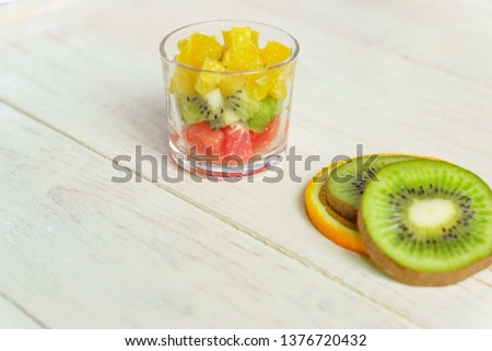 Diet Fresh tasty mix fruit salad in a glass jar on wooden table. Chopped juicy oranges, kiwi and grapefruits.