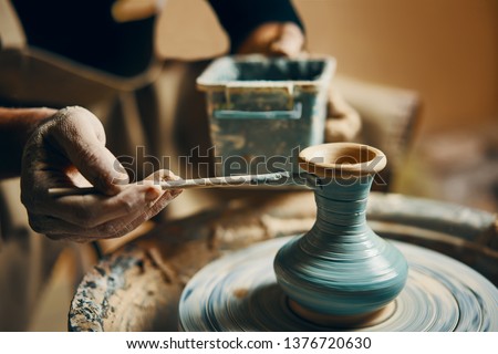 Man painting handmade pottery at ceramic workshop. Art concept Royalty-Free Stock Photo #1376720630
