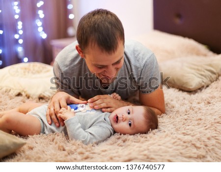 Happy father with his five mouth old dauhter playing at home on the bed. Portrait of a father with his baby - Image