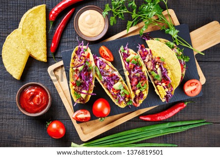 Delicious corn tacos with red cabbage, pulled bbq chicken, ripe avocado, corn, cilantro, red onion, paprika, chilli on top, close up, flat lay, with ingredients, horizontal view