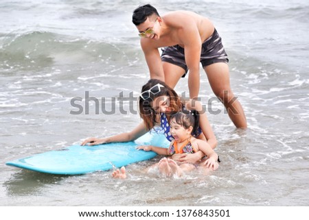 asia family father and mother and daughter happy life on the beach with surfboard, travel the sea in rayong thailand