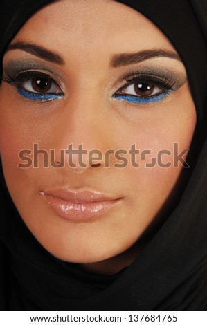 A pretty and young teen girl with a black headscarf and nice makeup looking into the camera in closeup, for white background. 