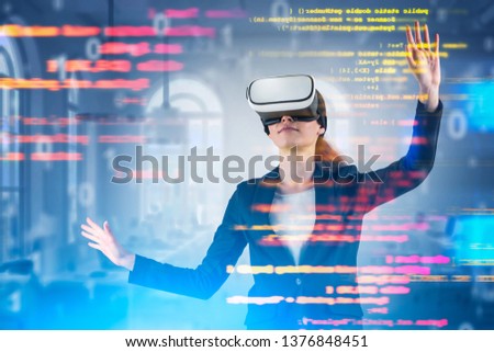 Young woman in virtual reality headset working with code over blurred office background. Concept of woman programmer and hi tech. Toned image double exposure