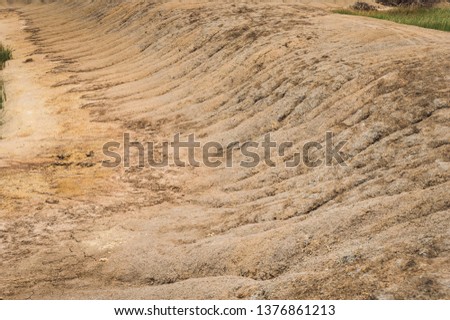 Arid landscape and Eroded soil concept. Background image of a dried cracked clay with traces from a erosion .Natural picture taken during the dry season.