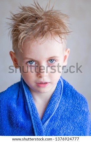 cute funny little boy with towel on his shoulders and wet hair in bathroom