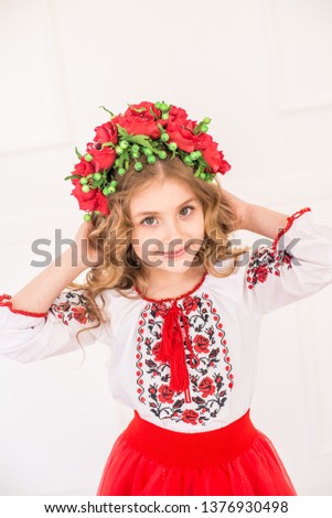 Little cute girl with blond curly hair in a national Ukrainian costume in a bright studio
