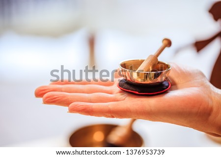 Small singing bowl holding in hand, blurry background