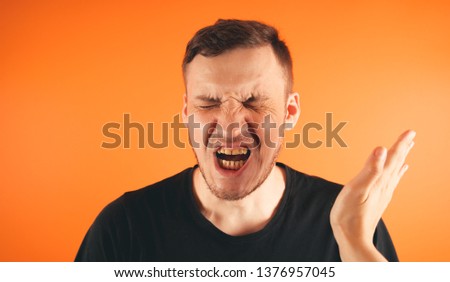 Man getting slapped on orange background. Unhappy scared man getting slapped standing on orange background Royalty-Free Stock Photo #1376957045