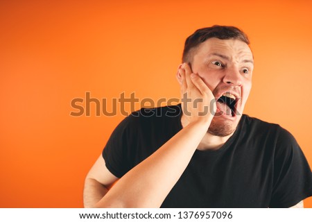 Man getting slapped on orange background. Unhappy scared man getting slapped standing on orange background Royalty-Free Stock Photo #1376957096