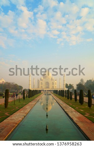                                This photo shows the beauty of Tajmahal with morning white clouds on blue sky and reflection in green waterbody 