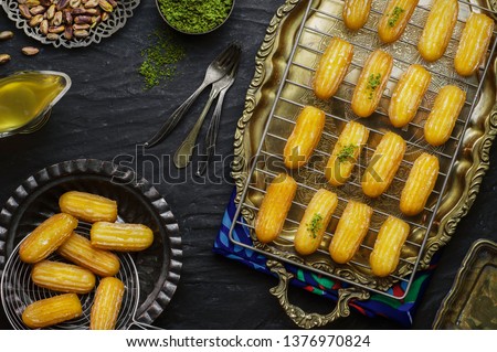 Arabic Cuisine: Middle Eastern traditonal dessert/Ramadan dessert "Balah Al-Sham" or "Balah El Shaam"  served with honey syrup and pistachio. Top view with copy space. Royalty-Free Stock Photo #1376970824