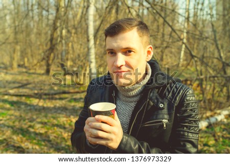 Man drinking coffee in cold woods
Casual man in outwear enjoying hot drink in paper cup standing in sunny seasonal forest