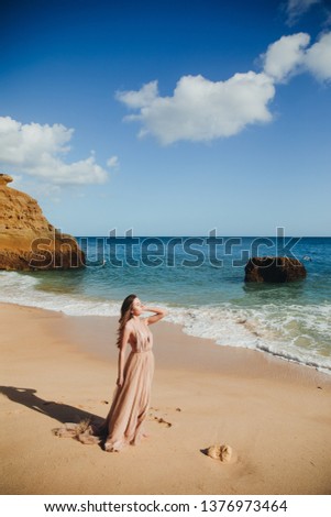 Young beautiful woman in long  dress on coast of sea. 