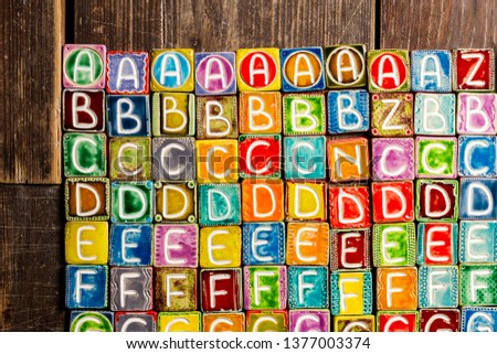 Colorful handmade ceramic alphabet on wood texture