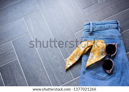 Blue denim clothes, sunglasses, animal print belt and trendy mustard yellow ribbon for hair on the light grey wooden background. Mockup for fashion blog