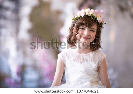 Portrait of a beautiful girl of six years. In a white dress with a wreath of flowers on his head.