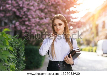 A portrait of  student at campus . Beautiful smiling girl with books in her hands. Spring concept