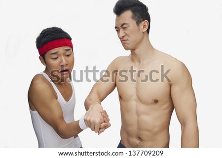 One young man beating another at arm wrestling, studio shot