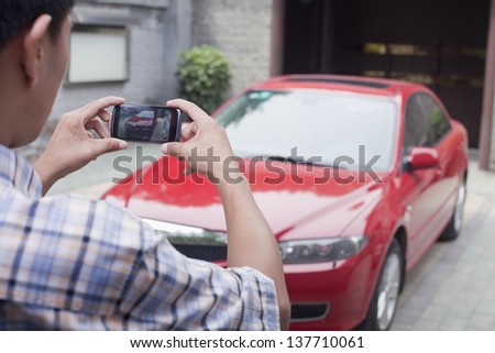 Young Man Taking a Picture of His Car