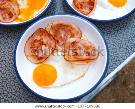 Breakfast, ham and fried egg On a white-blue plate and camping