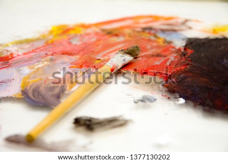 brush on wooden palette. Texture mixed oil paints in different colors. Instruments tools for creative leisure. Painting hobby background. Paintings art concept. Copy space.