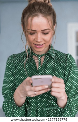 Closeup portrait of blonde girl with a smartphone and looking at the screen.- Image