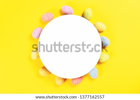 Colorful decorated easter eggs on bright yellow background with paper white circle as a frame with copy space for text. Easter holiday and tradition concept. Flat lay style.