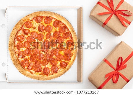Delivery Pizza pepperoni in cardboard box top view for promotions and discounts with copy space isolated on white background. Fast Food delivery. Gift pizza with red ribbon.