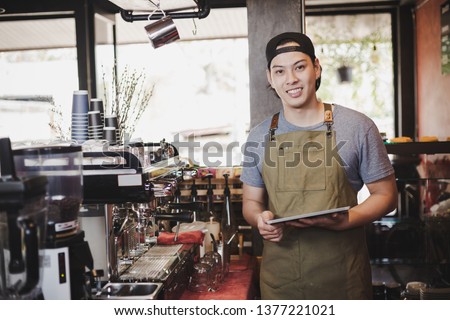 asian man barista holding tablet for checking order from customer on coffee cafe. Royalty-Free Stock Photo #1377221021