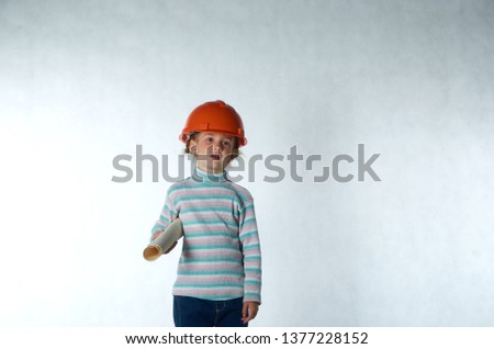 Little girl Builder playing with construction helmet and paper.
