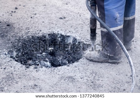 Closeup of a photo of professional workers in uniform repairing asphalt road with a jackhammer. Concept renovation, major repairs of the main street in city, road construction, pits
