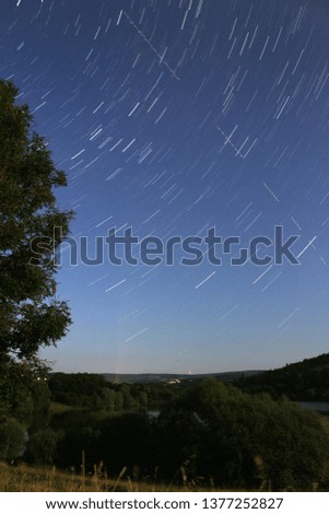 Startrails on bright blue sky with beautiful landscape in the forground