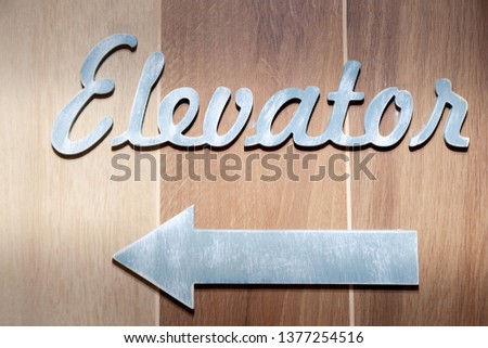Silver metal letters, pointer of elevator, lift sign on the wall hotel, lobby. Concept sign, cursor, inscription at the five star hotel