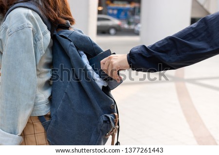 Cropped image of hands of pickpocket thief stealing wallet from backpack of tourist girl Royalty-Free Stock Photo #1377261443