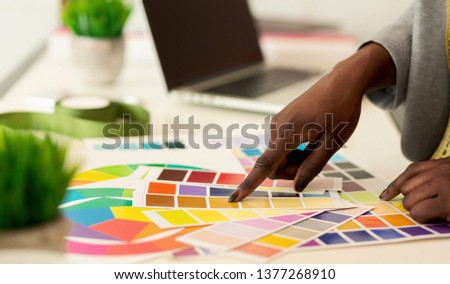 New collection. Fashion designer choosing colors, pointing on swatches pallet, closeup